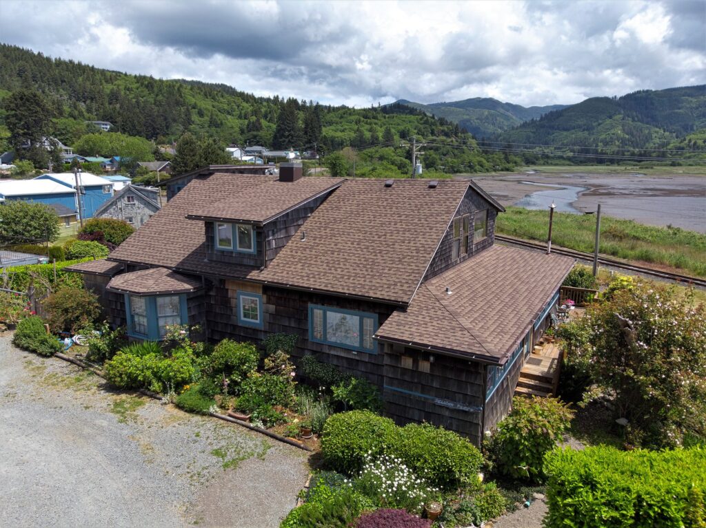 Overhead view of a house with a brown roof and water in the background.