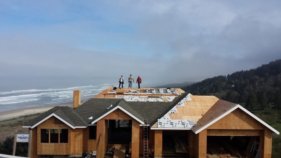 Guys on a roof with the ocean in the background.