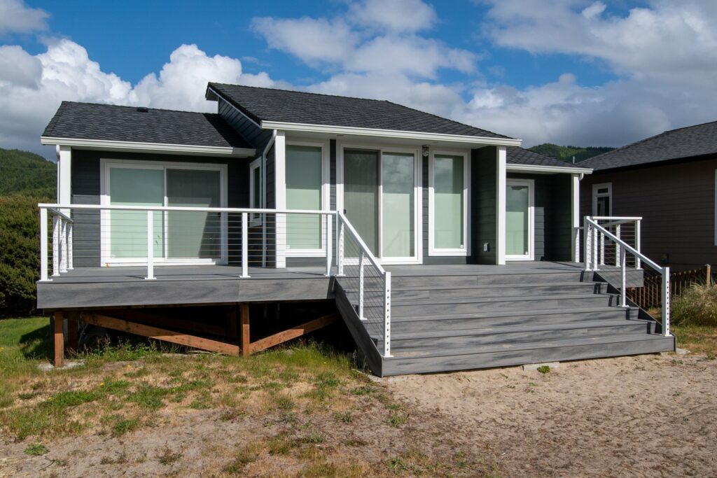 A grey house with a large deck and stairs.